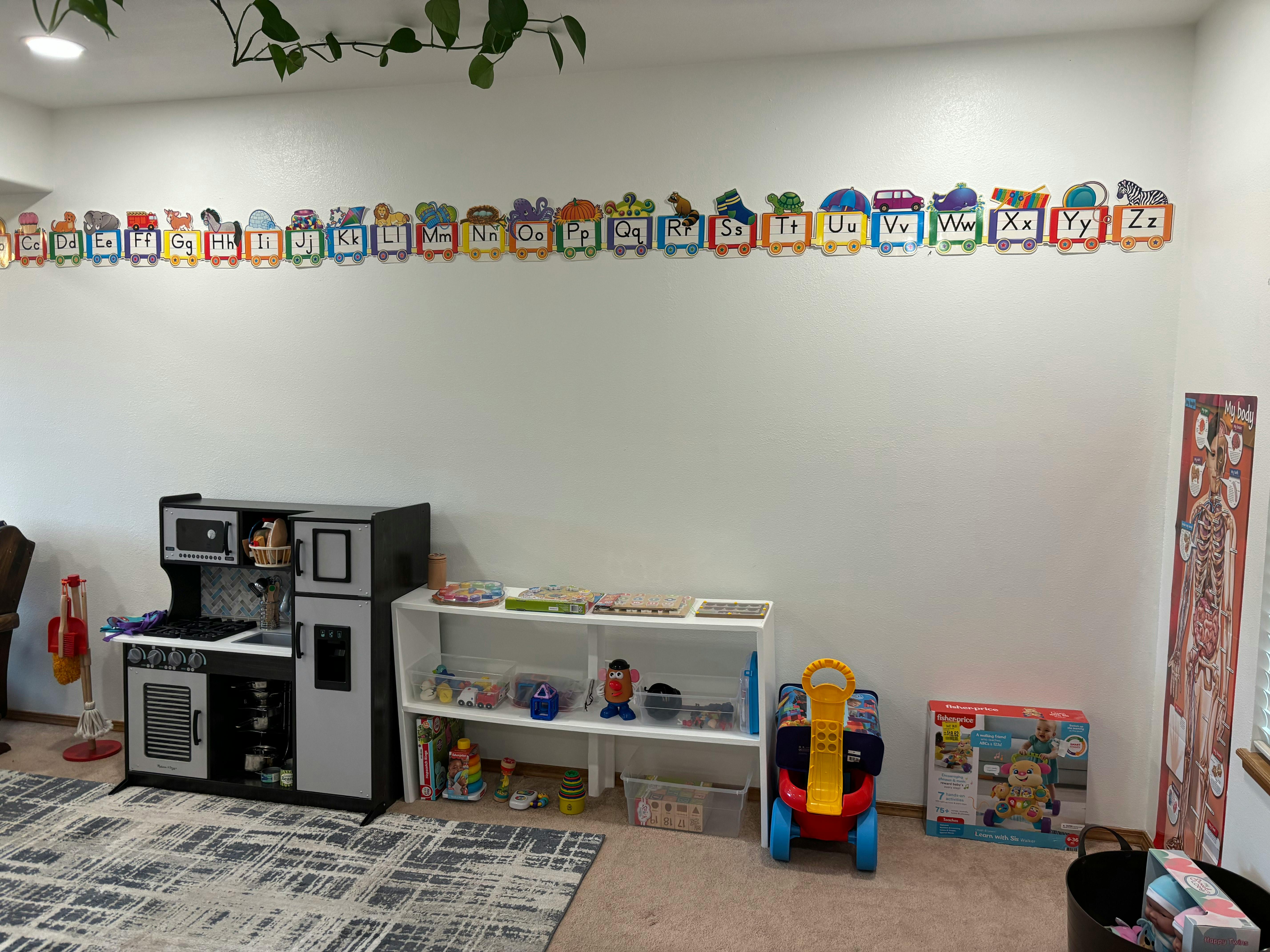 Play kitchen and toy shelf in a room with alphabet train decorations