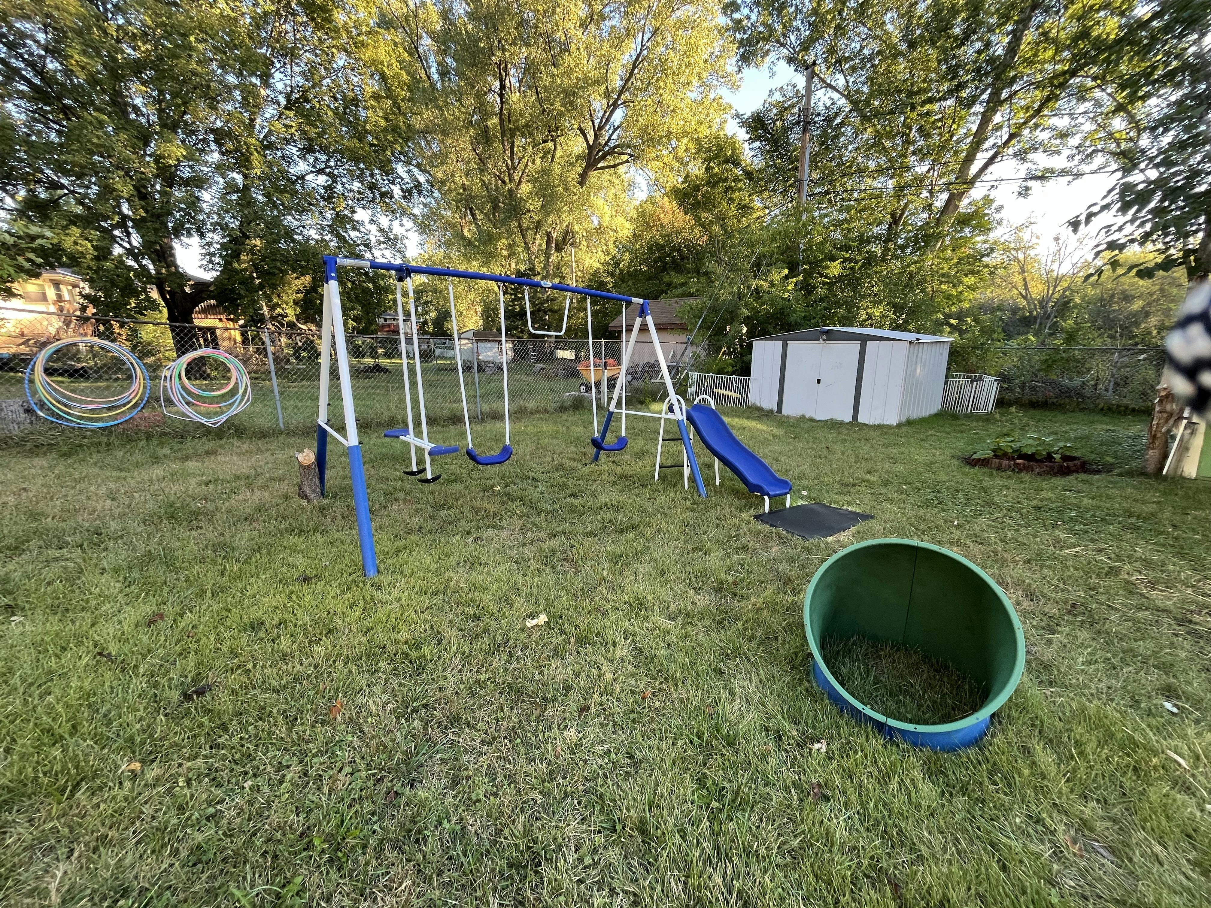 Swingset with a slide and a play tunnel in a grassy backyard