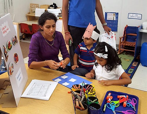 Person and two children at a table with craft supplies