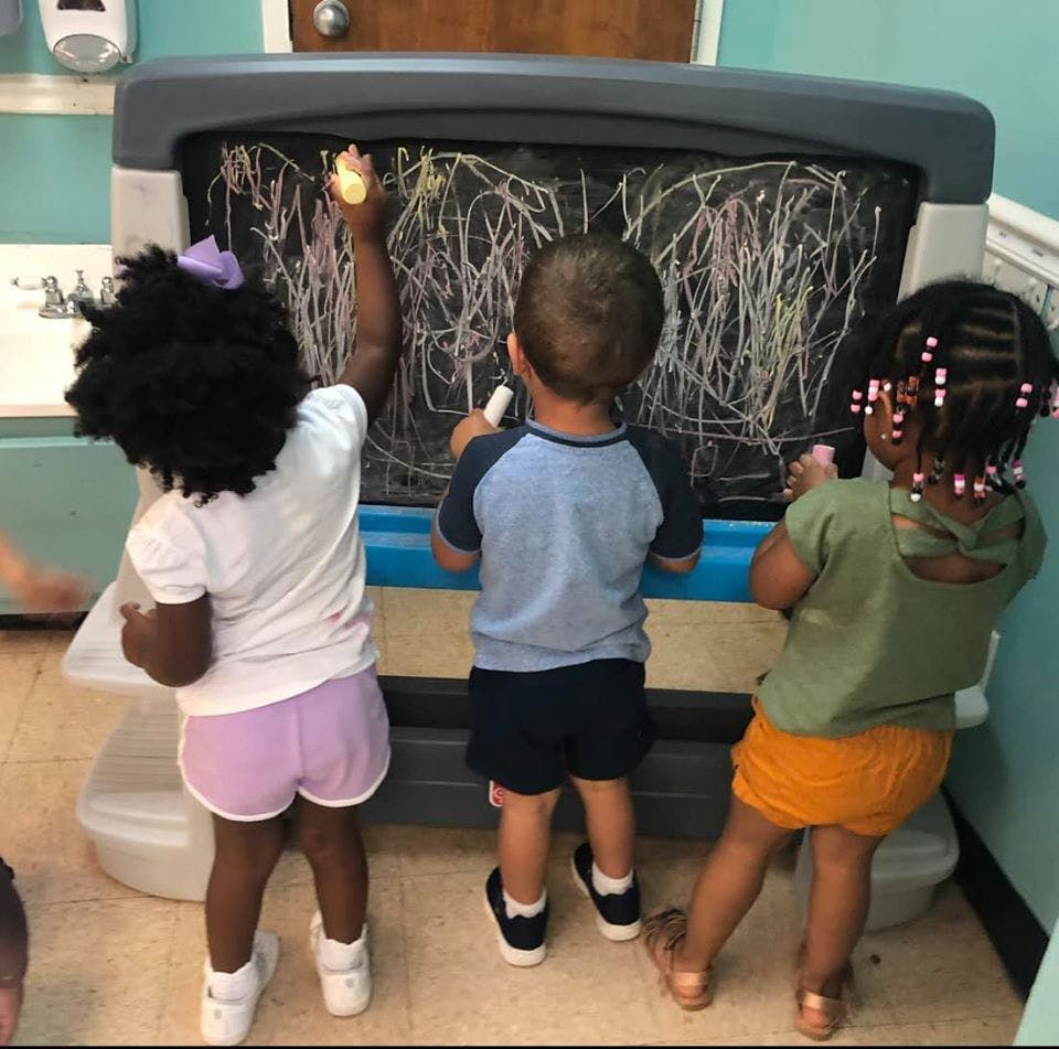Three children drawing on a chalkboard