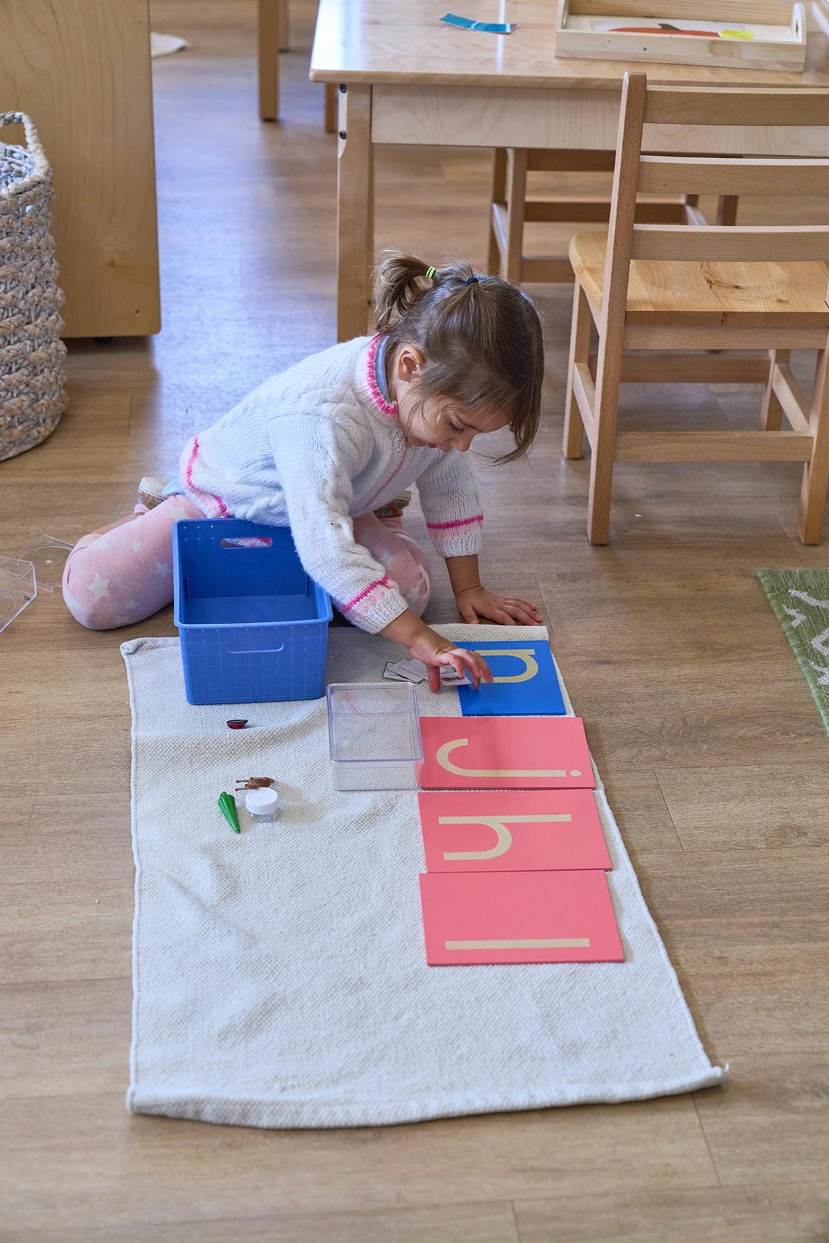 Child on floor playing with alphabet cards