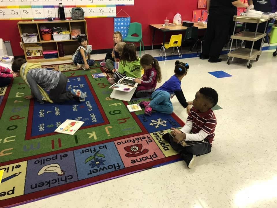 Children sitting on a colorful rug in a classroom