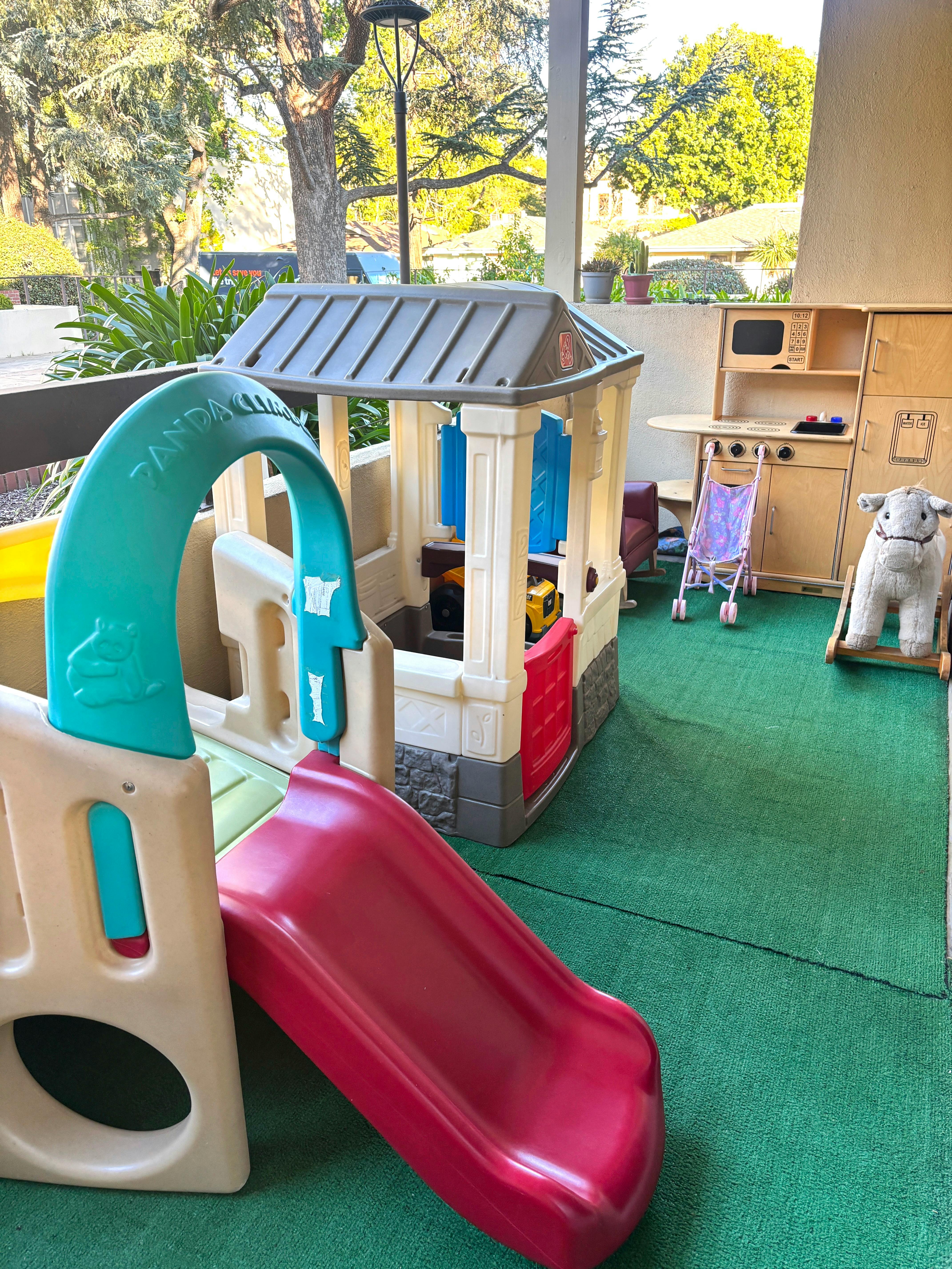 children's play area with a slide, playhouse, toy kitchen, and rocking horse