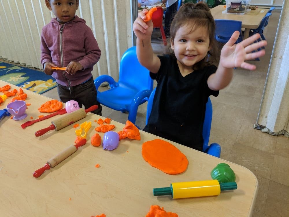 Two children playing with modeling clay at a table