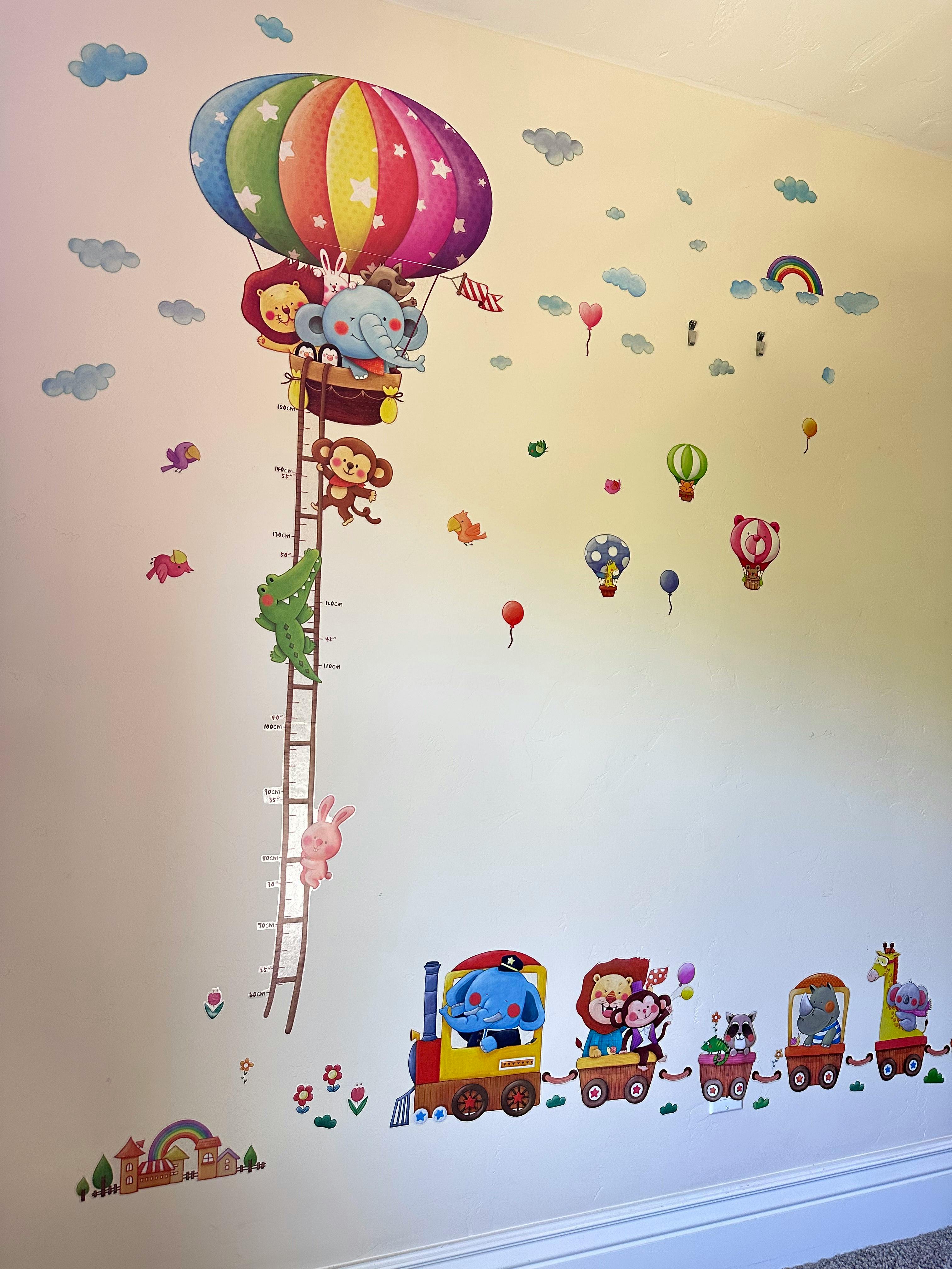 Wall decals of animals in a hot air balloon and a train, with a height chart