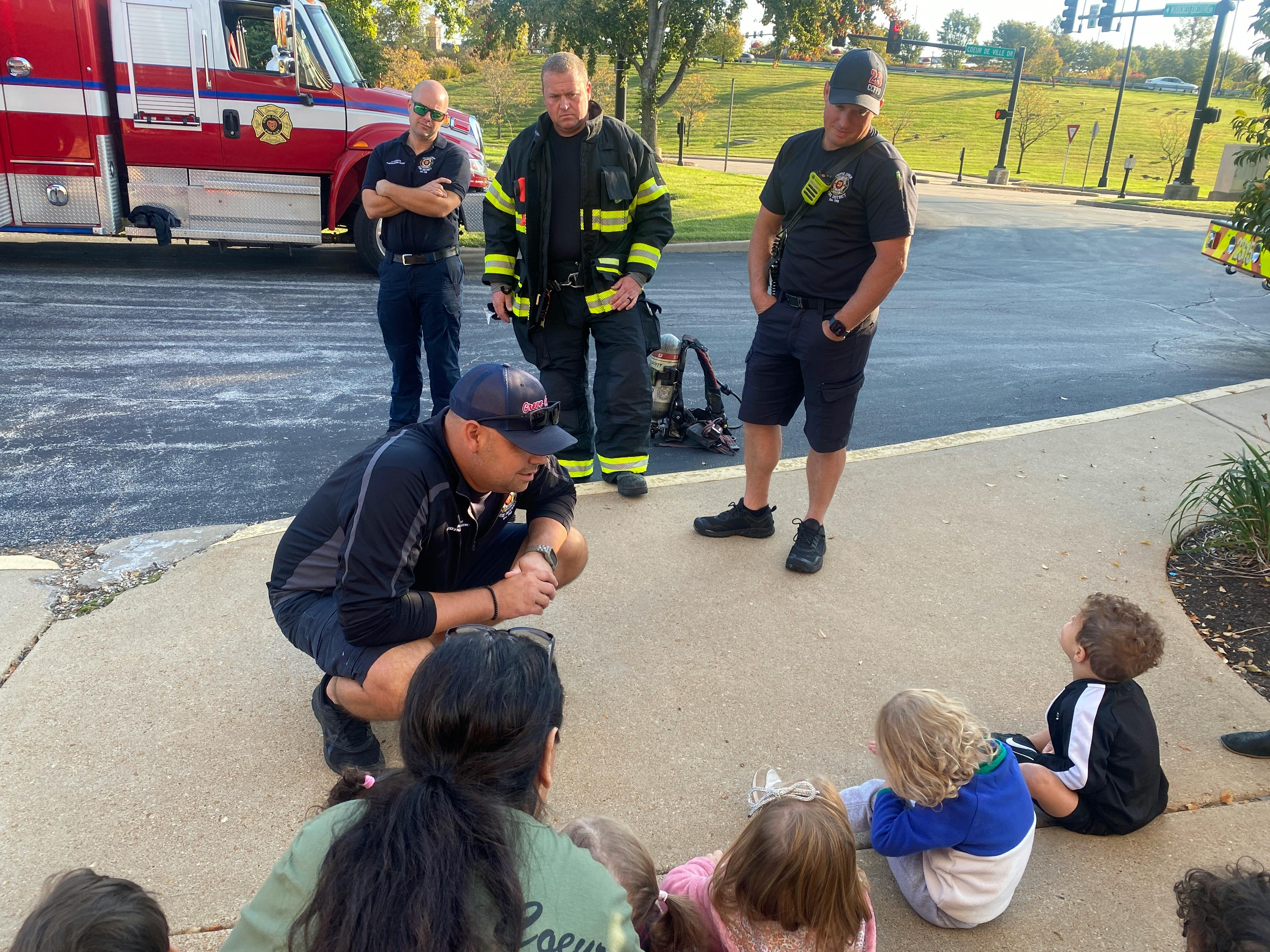 Adults in uniform interacting with children on the ground