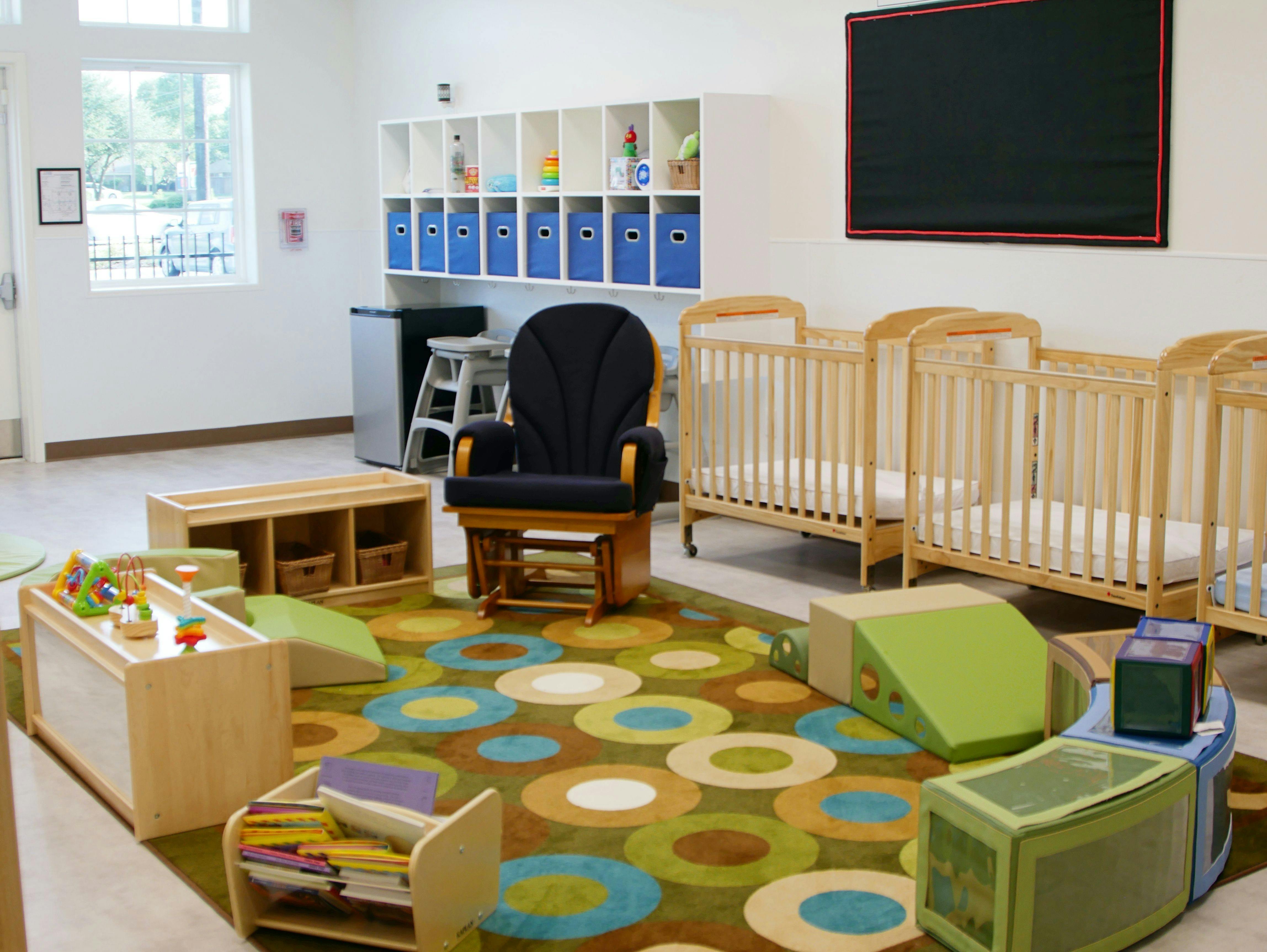 Nursery room with cribs, a rocking chair, and a colorful rug
