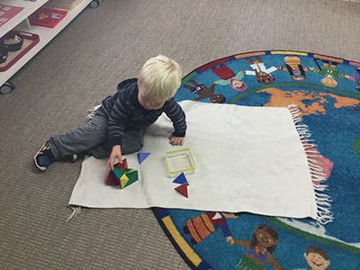Child playing with colorful geometric blocks on a rug