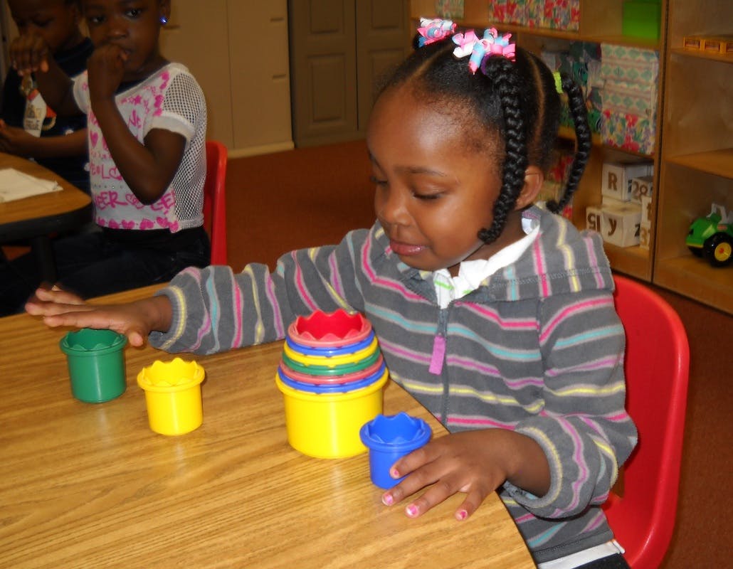 Child playing with colorful stacking cups at a table