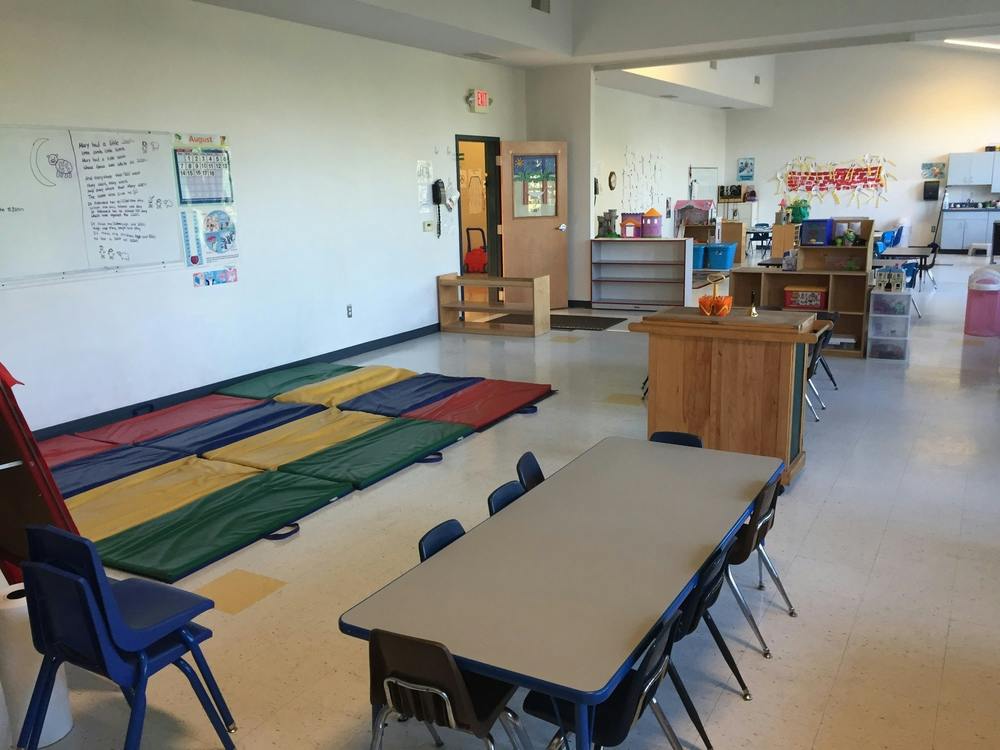 Empty classroom with colorful mats on the floor and tables with chairs