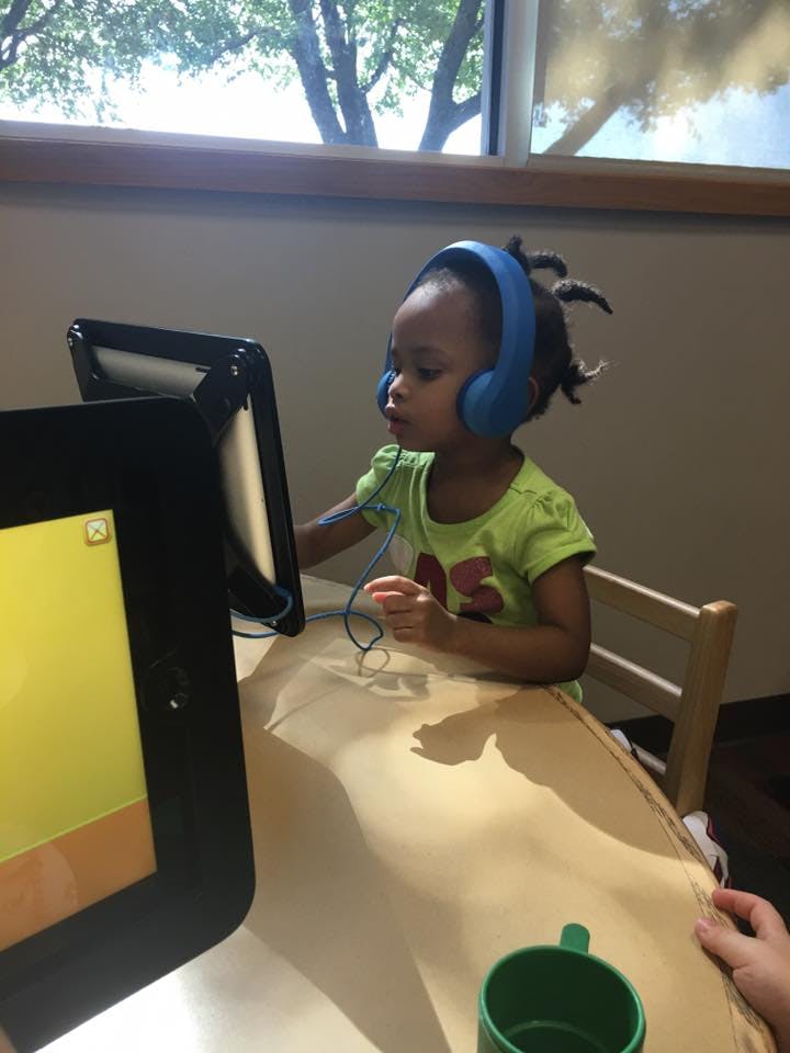 Child wearing headphones looking at a tablet