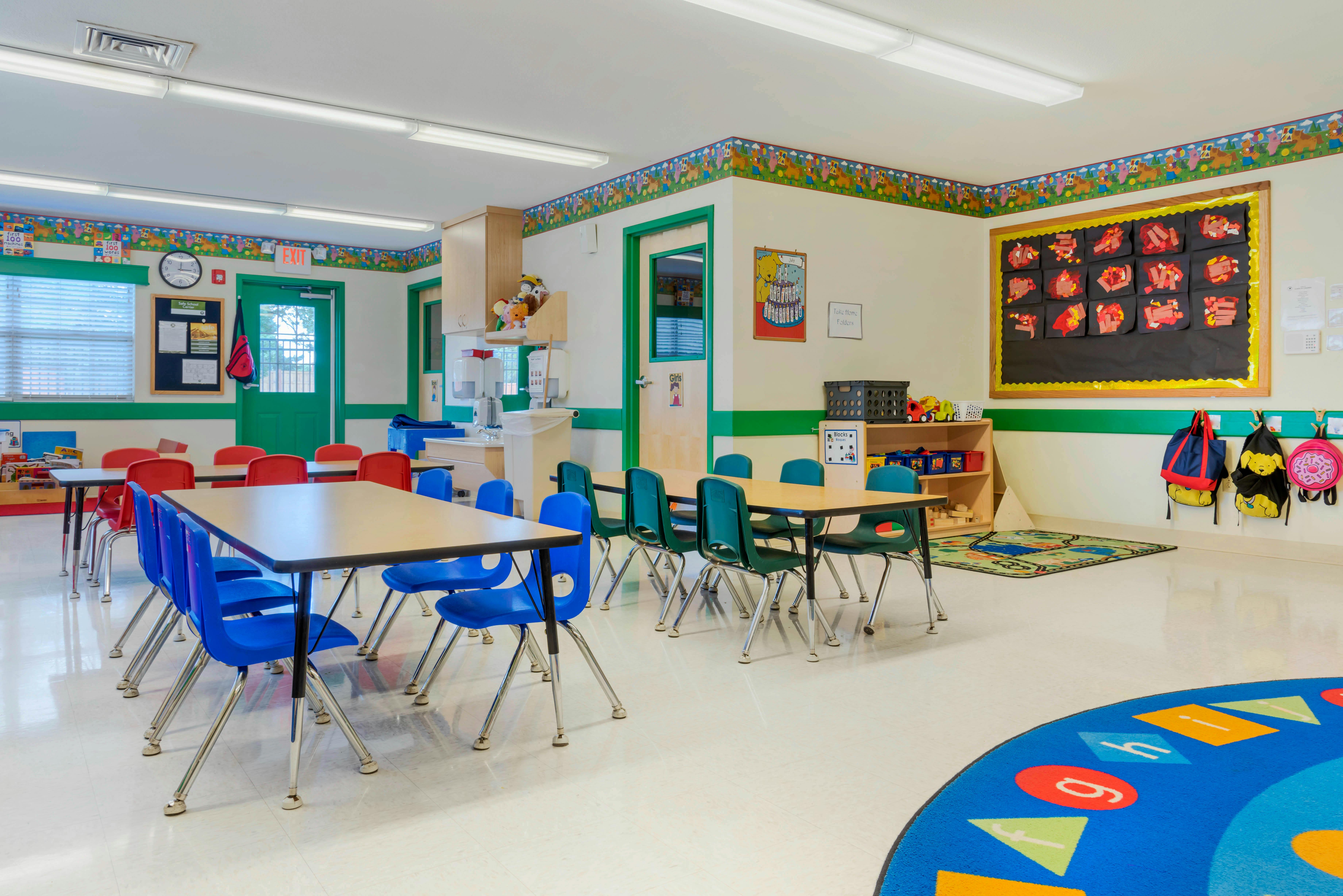 An empty classroom with small tables and chairs, and colorful decorations