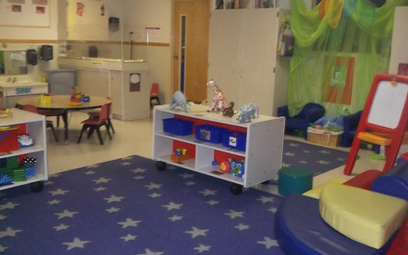 A colorful classroom with a blue star-patterned rug, small tables, and toys