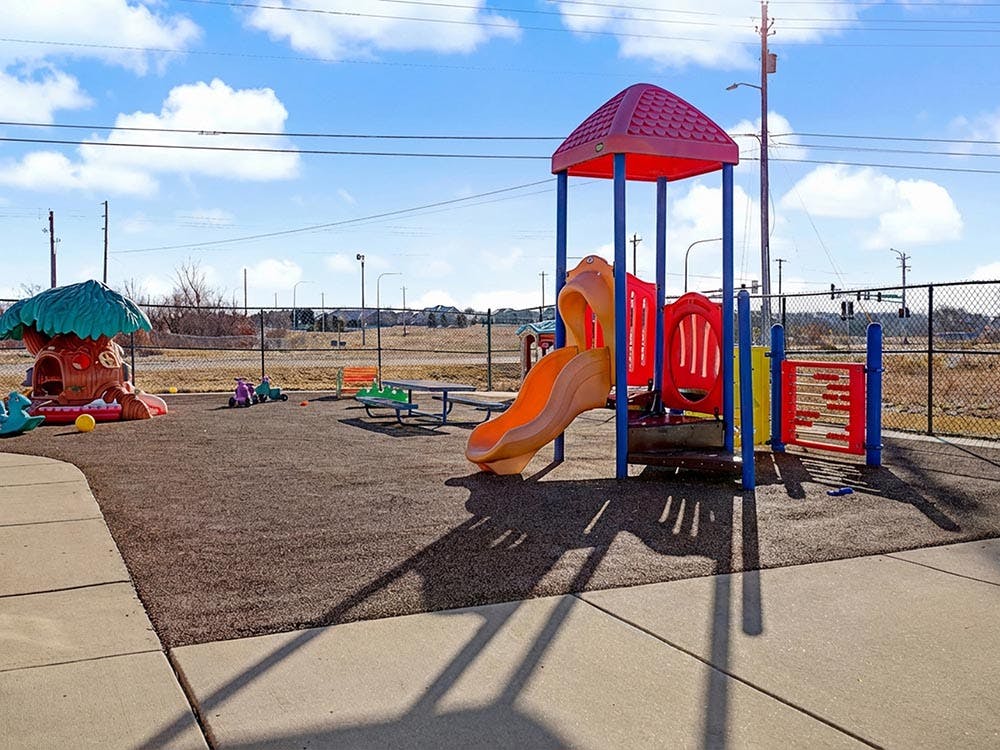 Playground with slide, playhouse, and riding toys on a sunny day