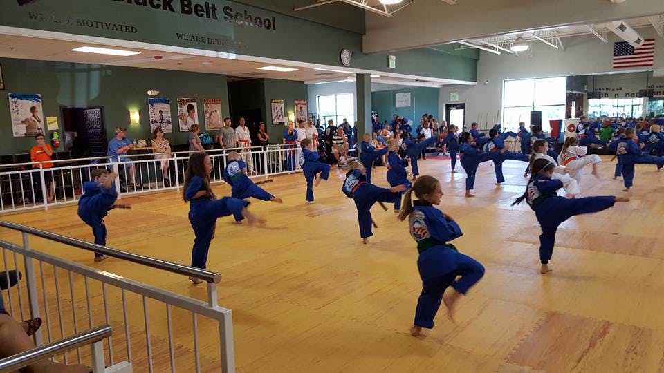 Group of children in blue uniforms practicing martial arts kicks