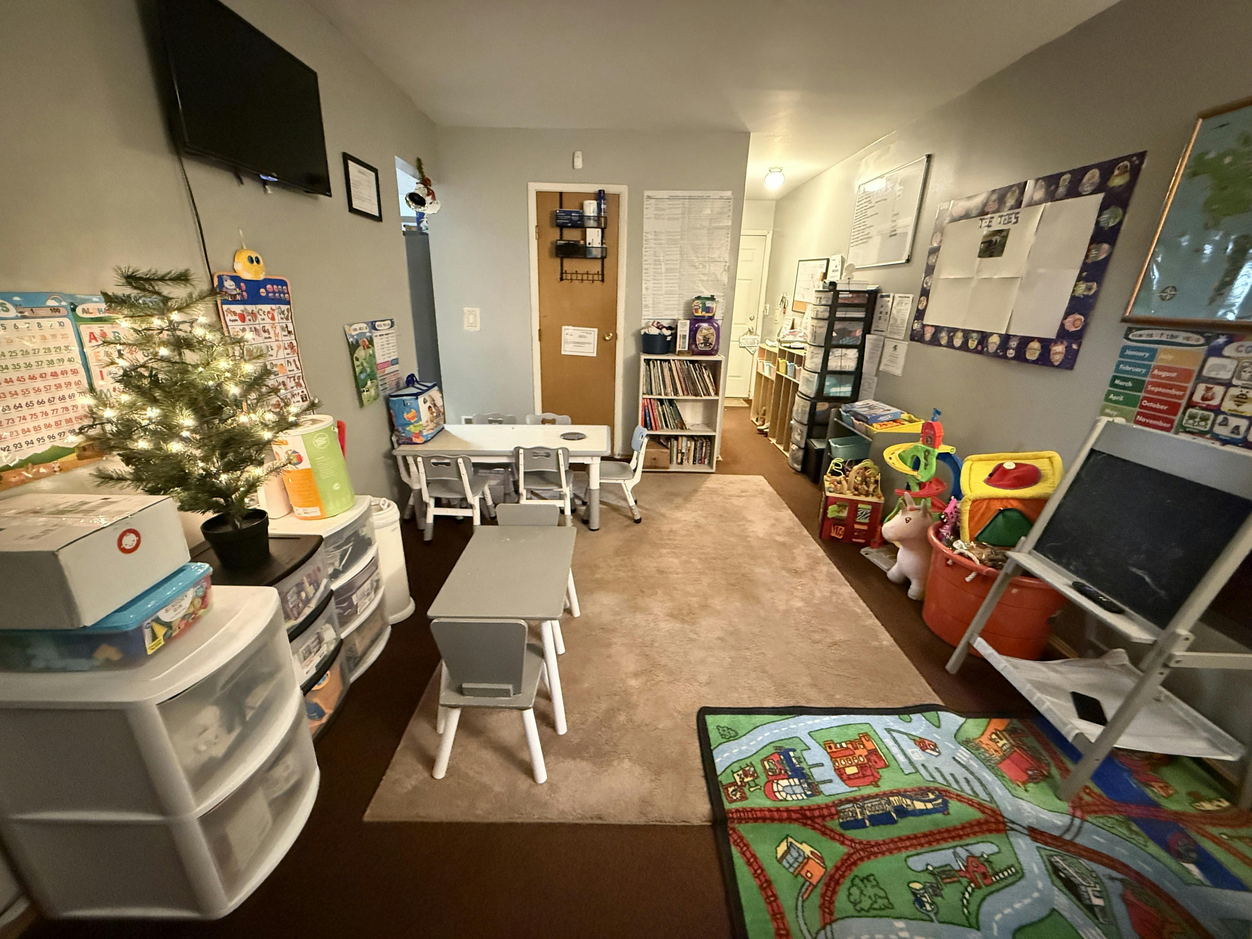 Classroom setup with small tables, chairs, toys, and educational posters