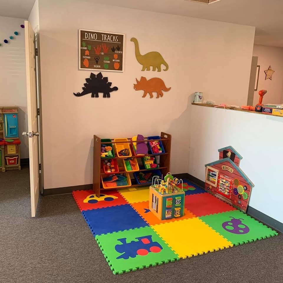Playroom with colorful floor mats, toy organizer, and dinosaur wall decor