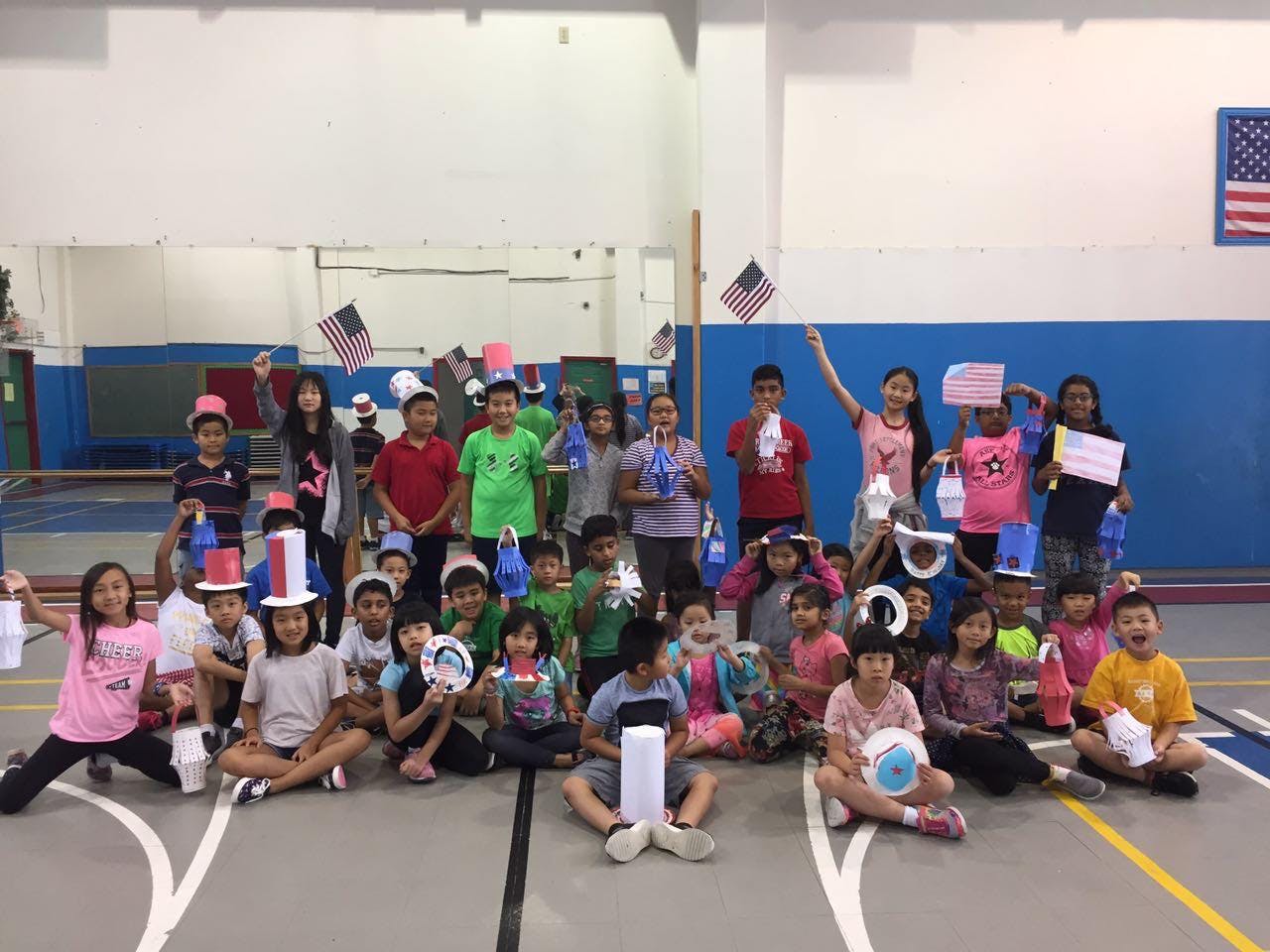Group of children holding American flags and crafts in a gym