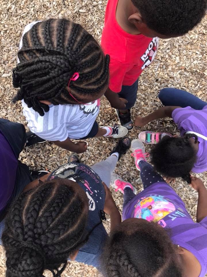 Children standing in a circle looking down at the ground