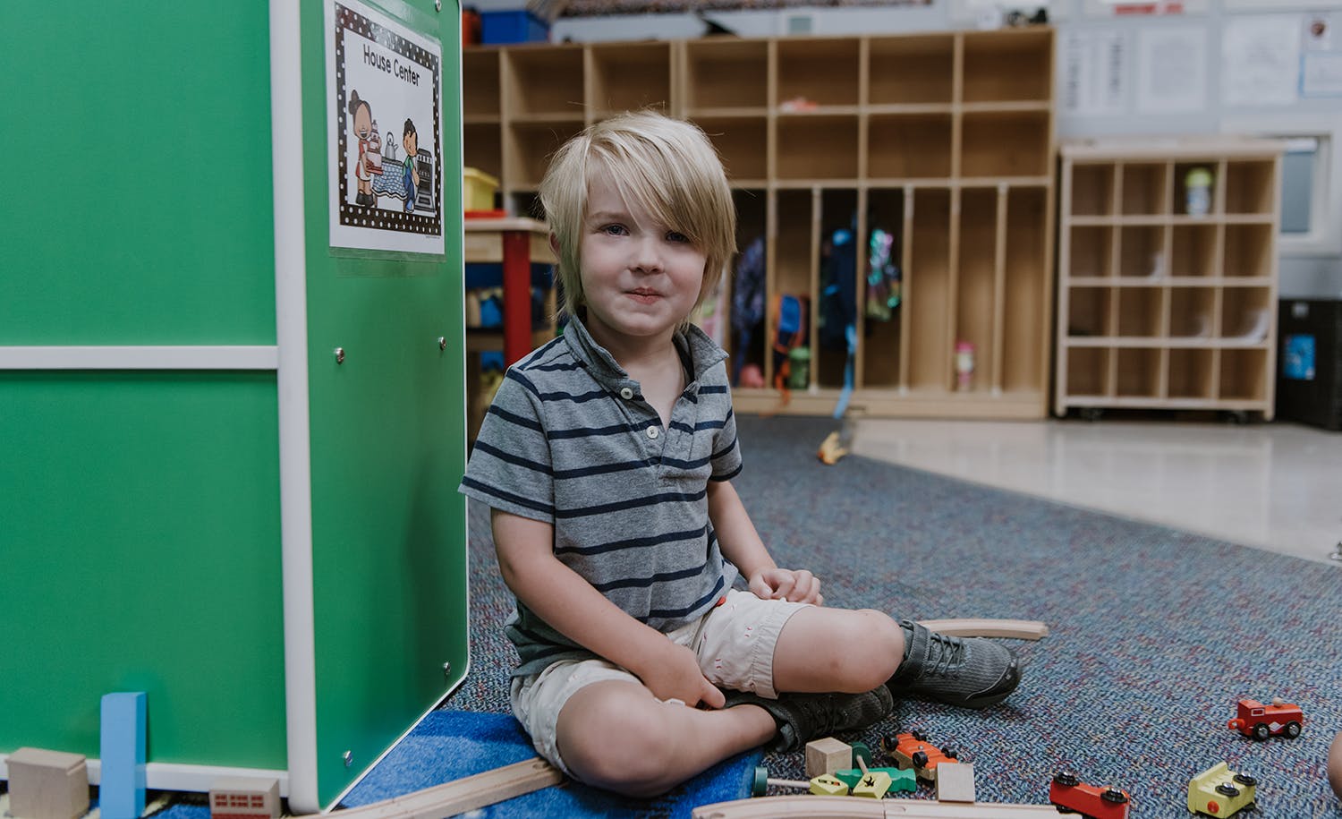 Child sitting on the floor in a classroom with toys