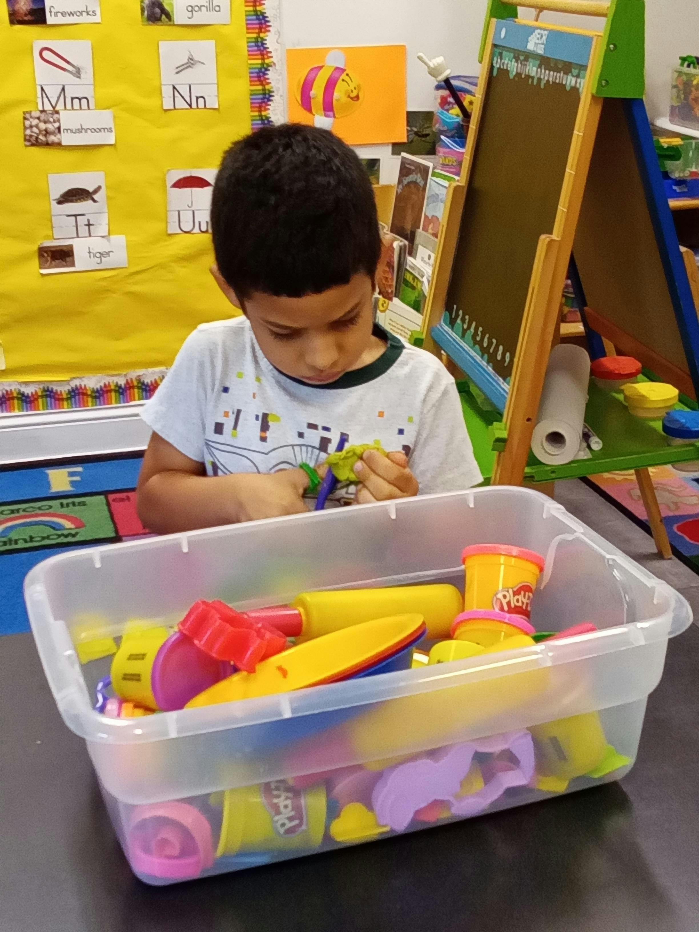 Child playing with colorful modeling clay tools in a classroom