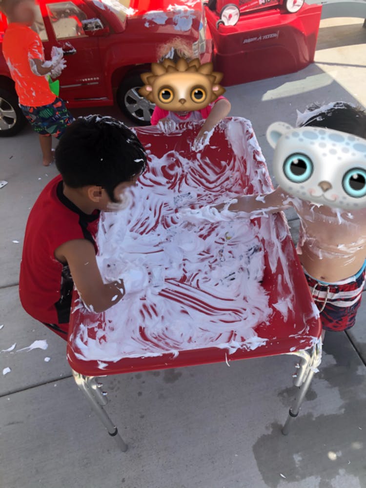 Child playing with shaving cream on a red table
