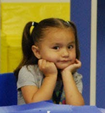 Child with pigtails resting chin on hands
