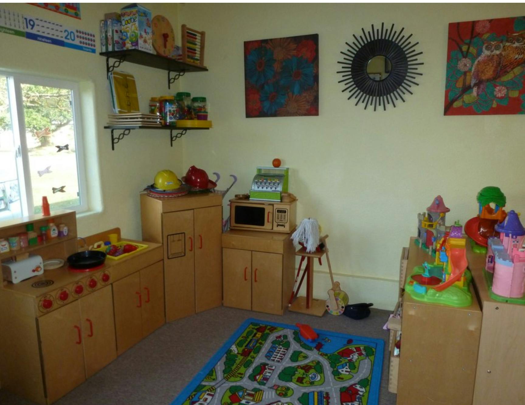 Playroom with toy kitchen, rug, and various toys