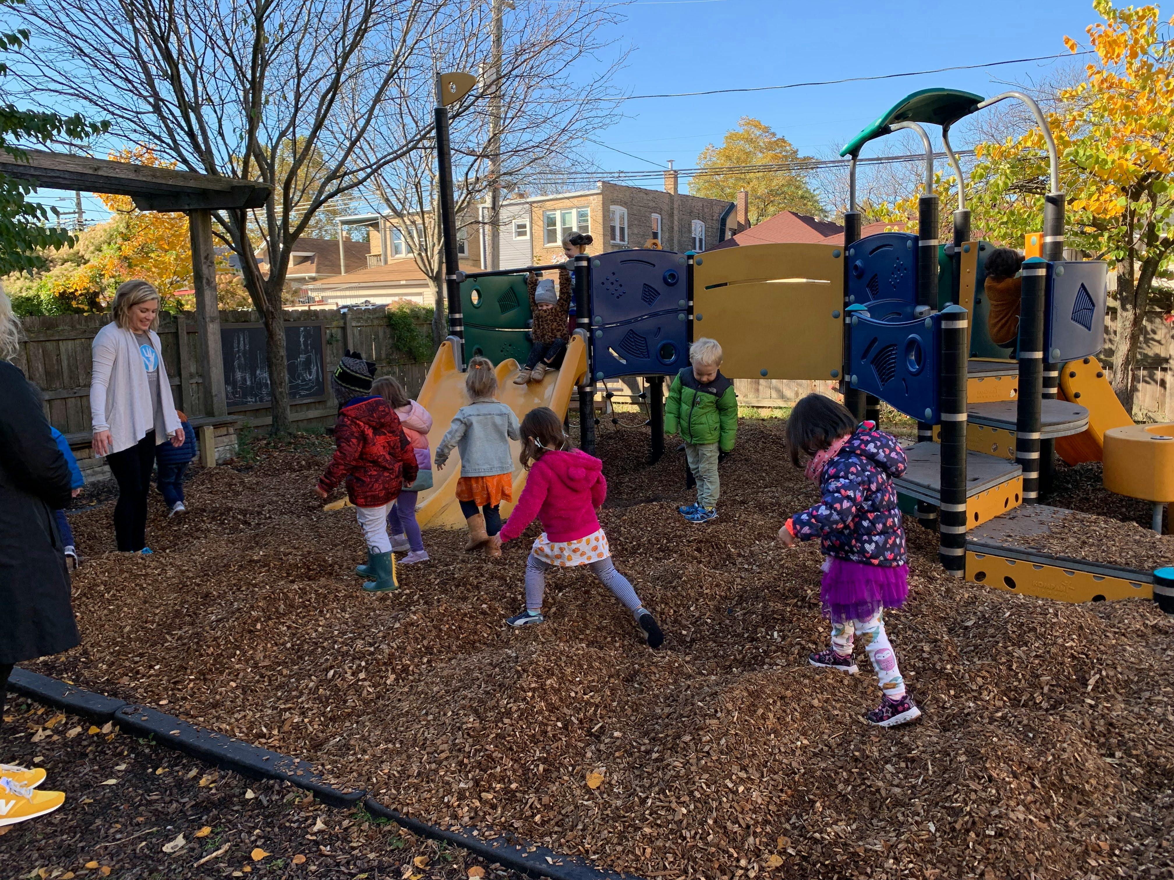 Children and adults on a playground with wood chips