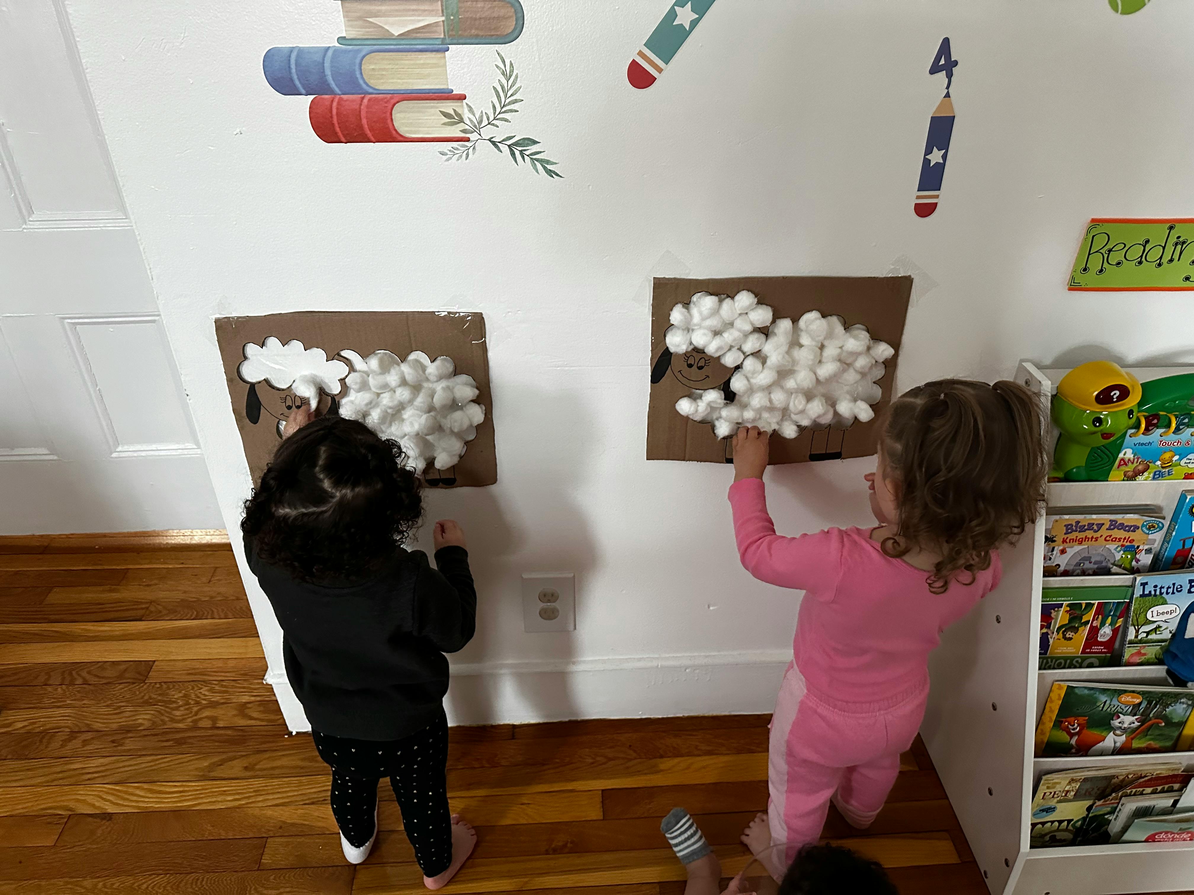 Two children making crafts with cotton balls on a wall