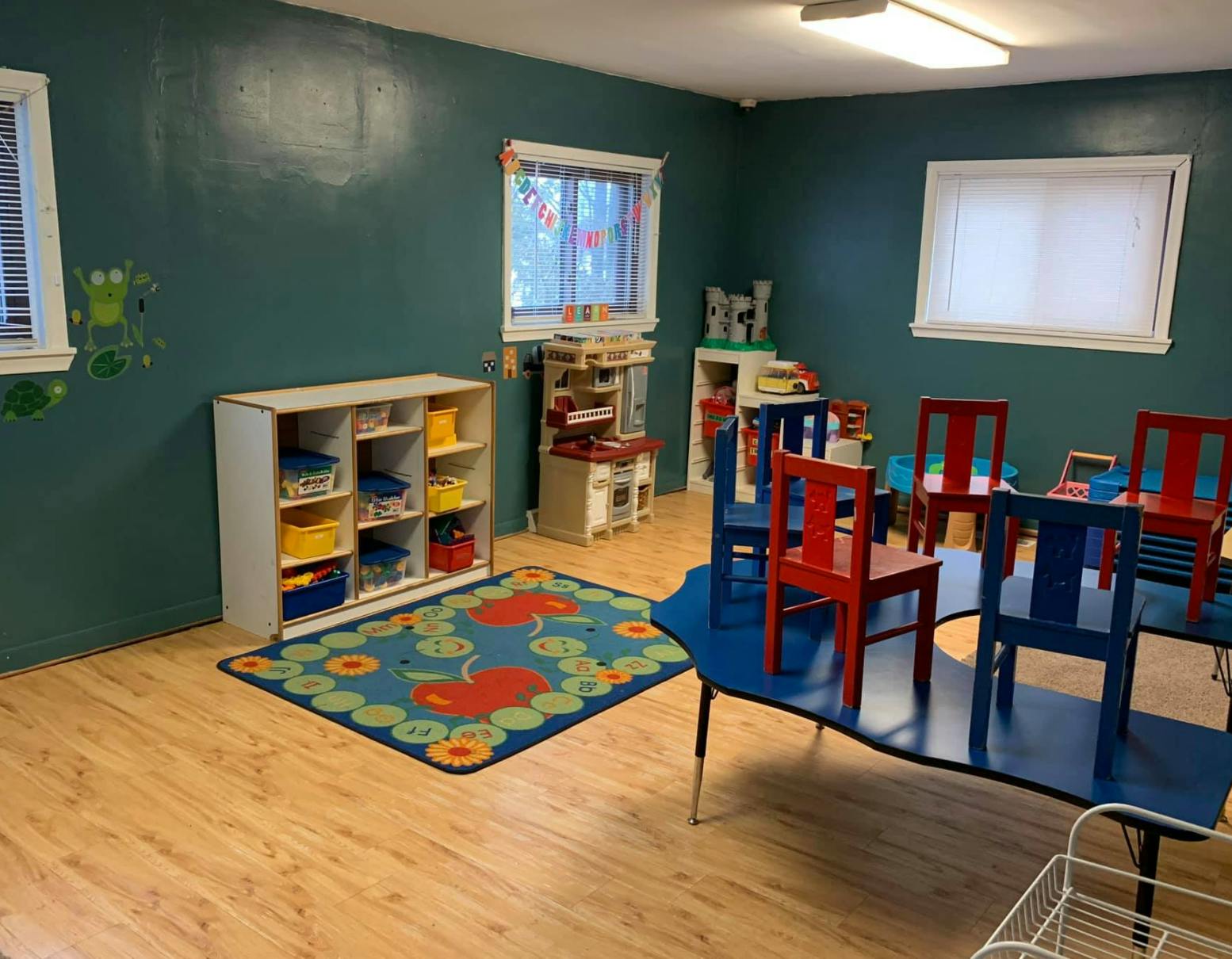 Classroom with small chairs and tables, storage unit, and rug