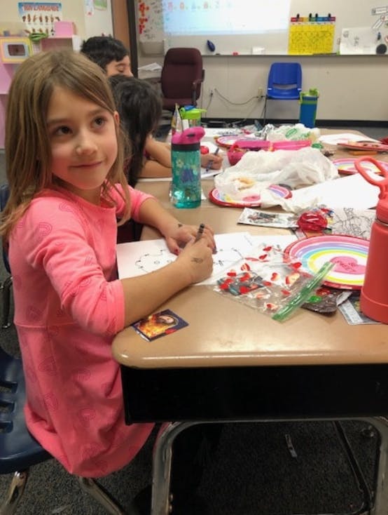 Child sitting at a desk and drawing on paper