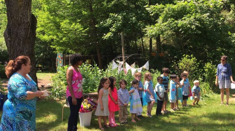Adults and children standing in a line outdoors