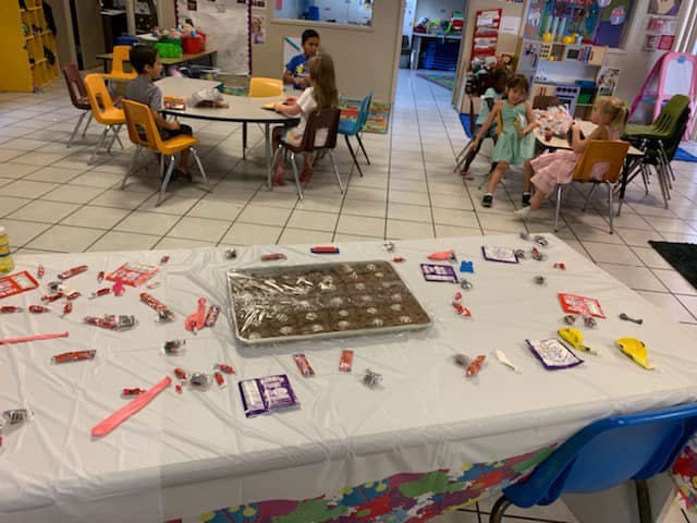 Table with candy and a baking sheet, children in background
