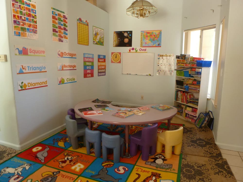 Classroom with small table and chairs, colorful rug, and educational posters