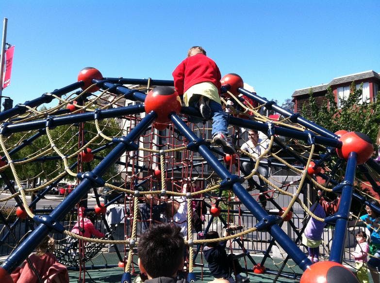 Child climbing on a playground dome climber