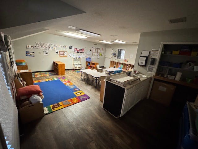 Empty classroom with small tables and a colorful alphabet rug