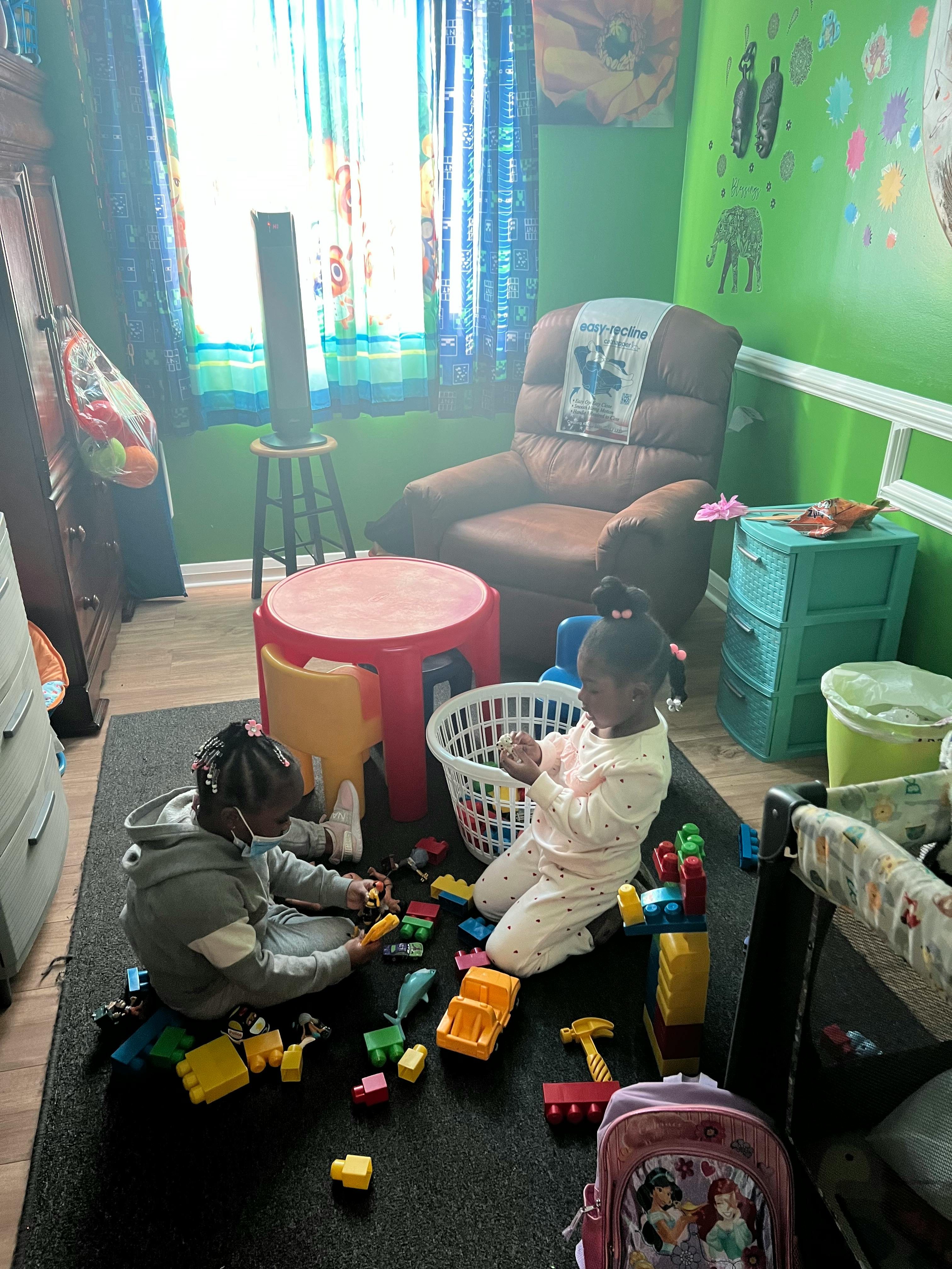 Two children playing with toys on a rug in a room