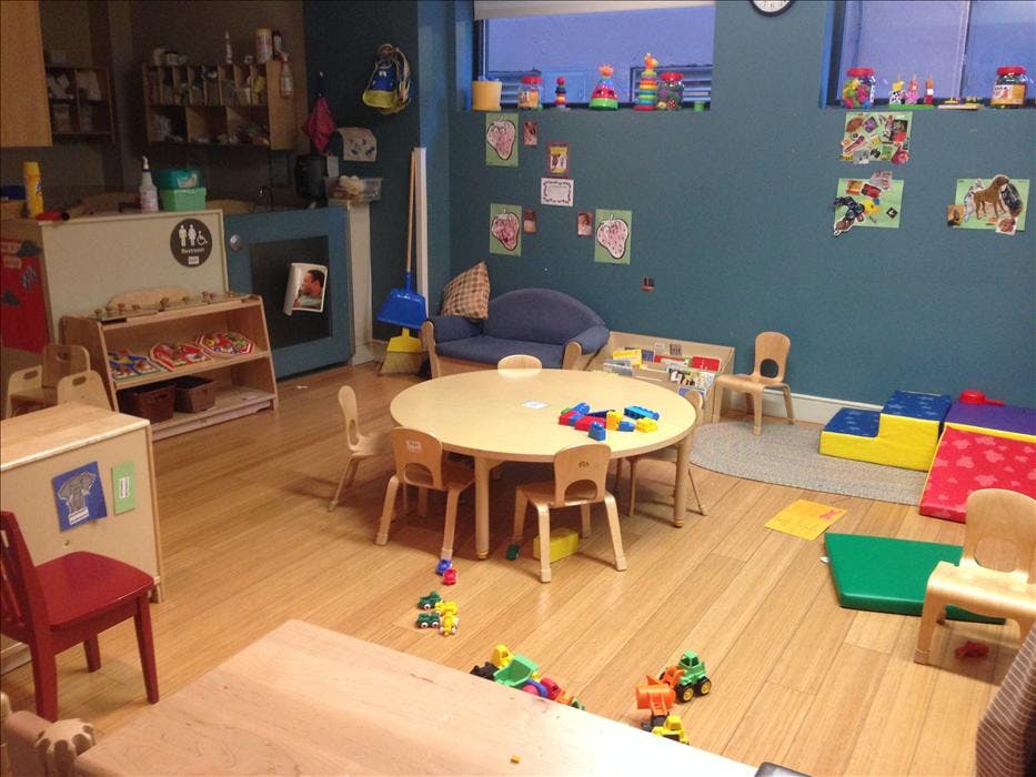A classroom with small tables, chairs, and toys scattered on the floor