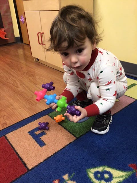 Child playing with colorful interlocking toys on a rug