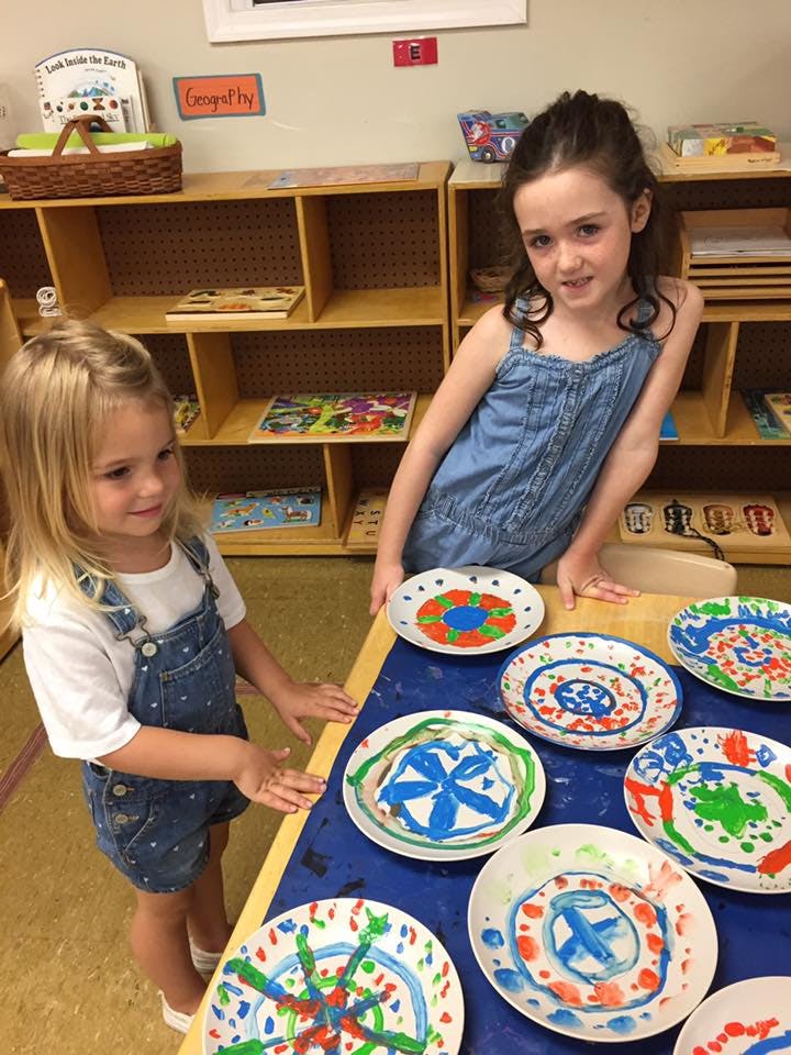 Two children standing at a table with painted paper plates