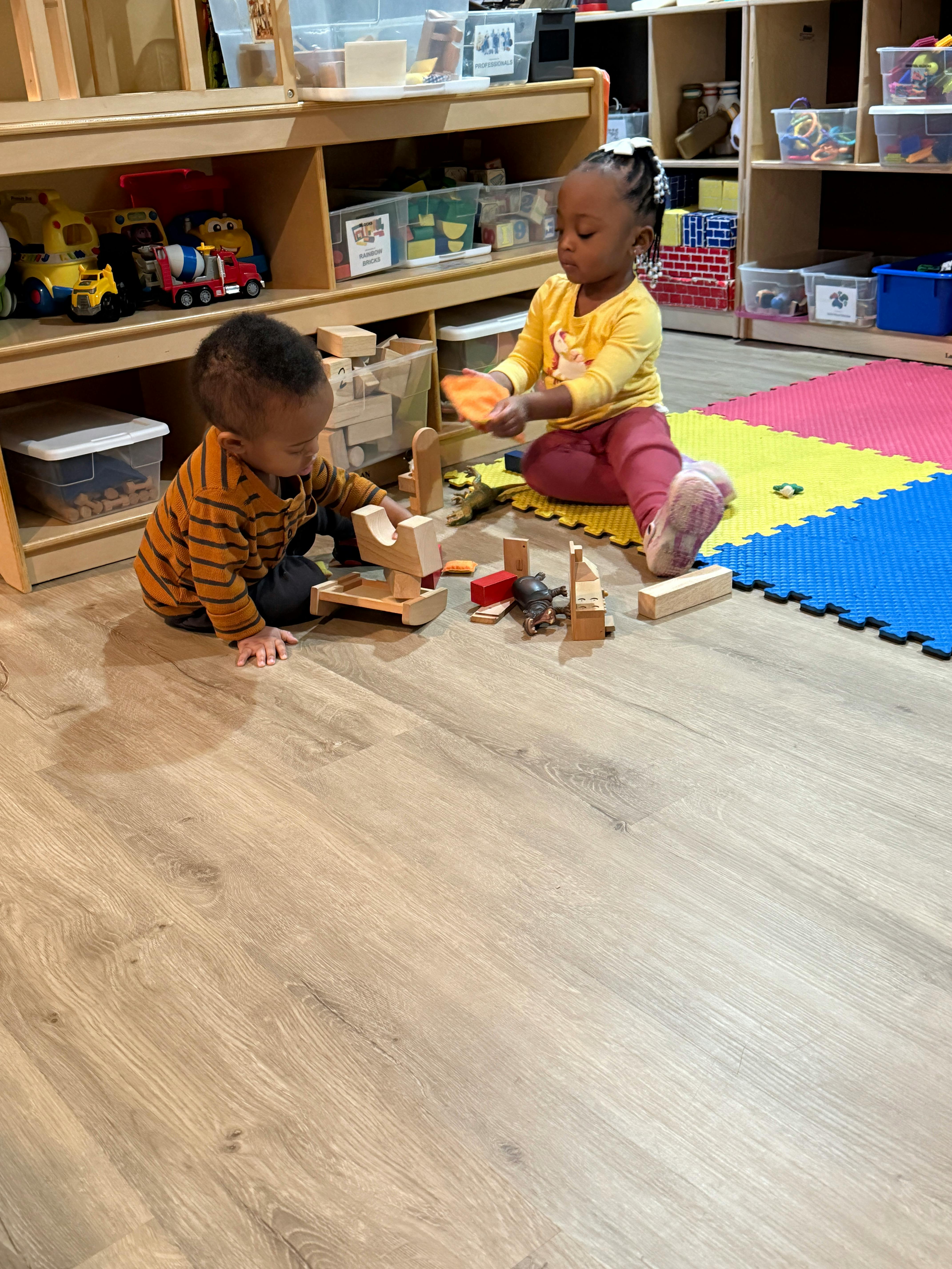 Two children playing with wooden blocks on the floor