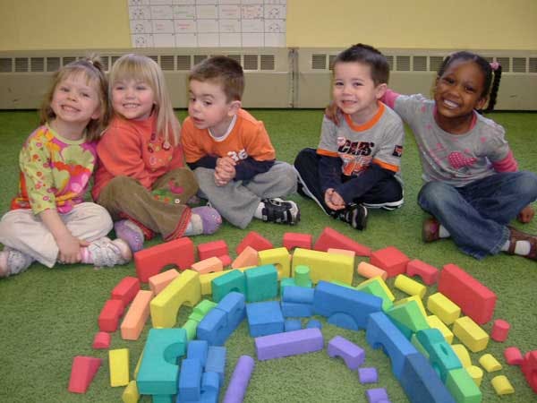 Four children sitting on the floor with colorful building blocks