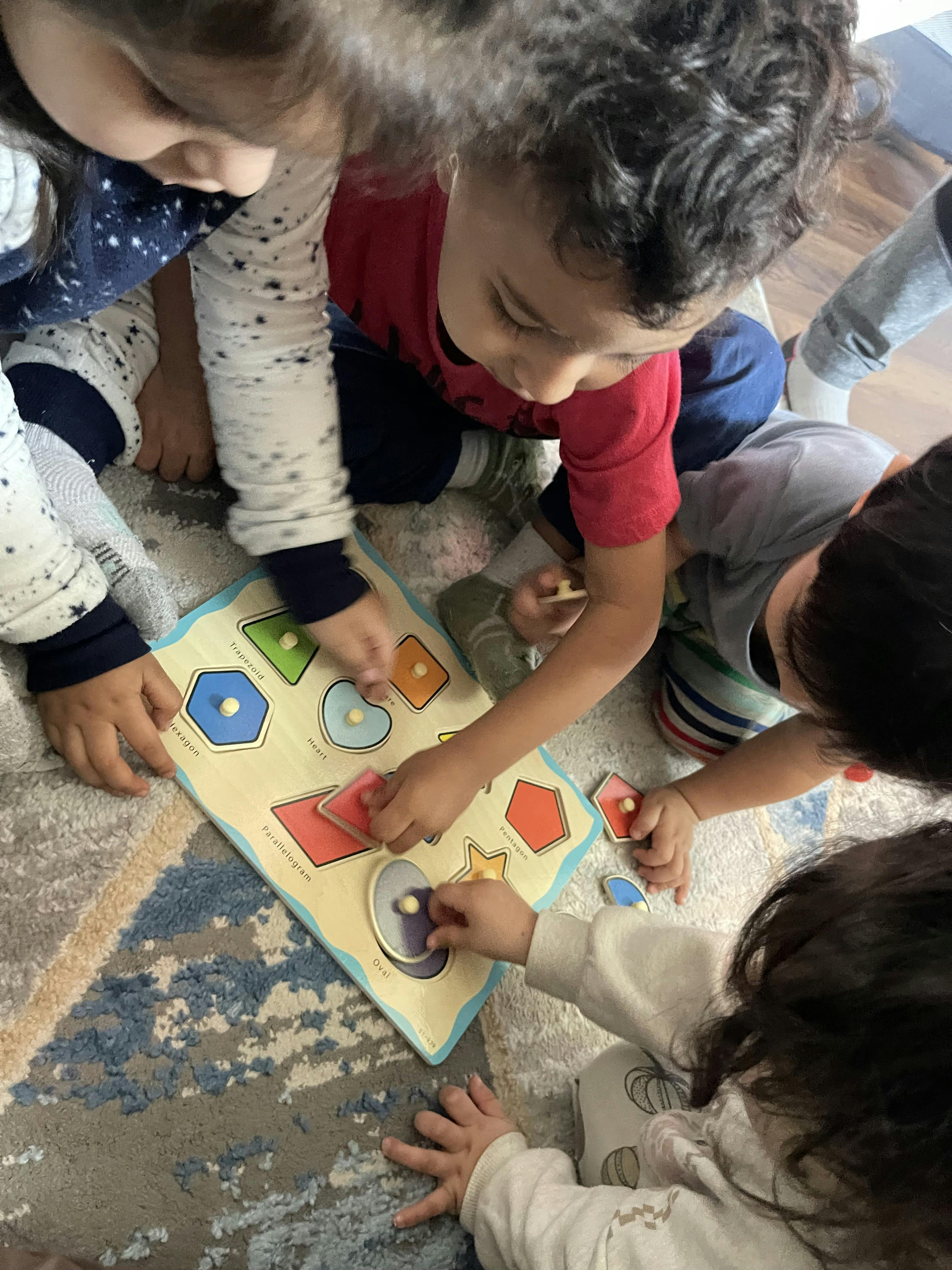 Several children playing with a wooden shape puzzle