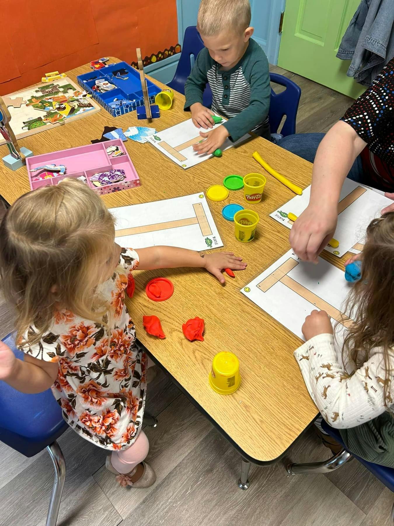 Children and an adult playing with playdough at a table