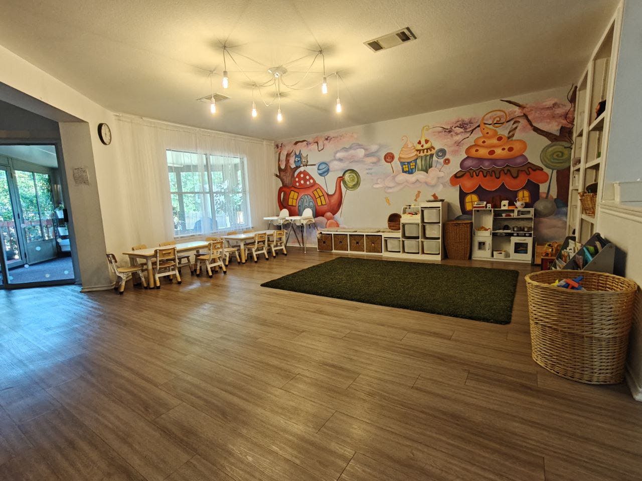 Playroom with small tables and chairs, a rug, and a mural on the wall