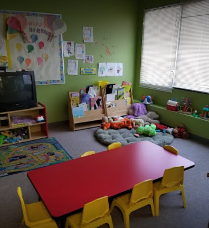 Classroom with a red table and yellow chairs, bookshelves, and toys