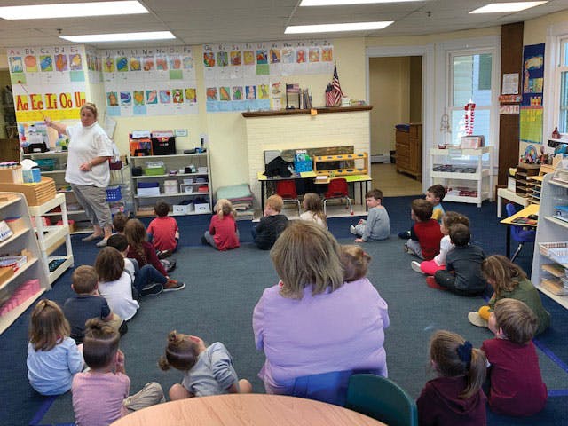 Adult teaching a group of children sitting on the floor in a classroom