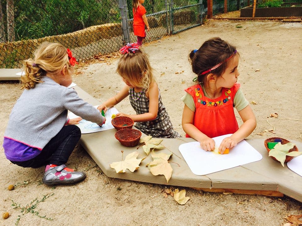 Three children doing an art activity outdoors