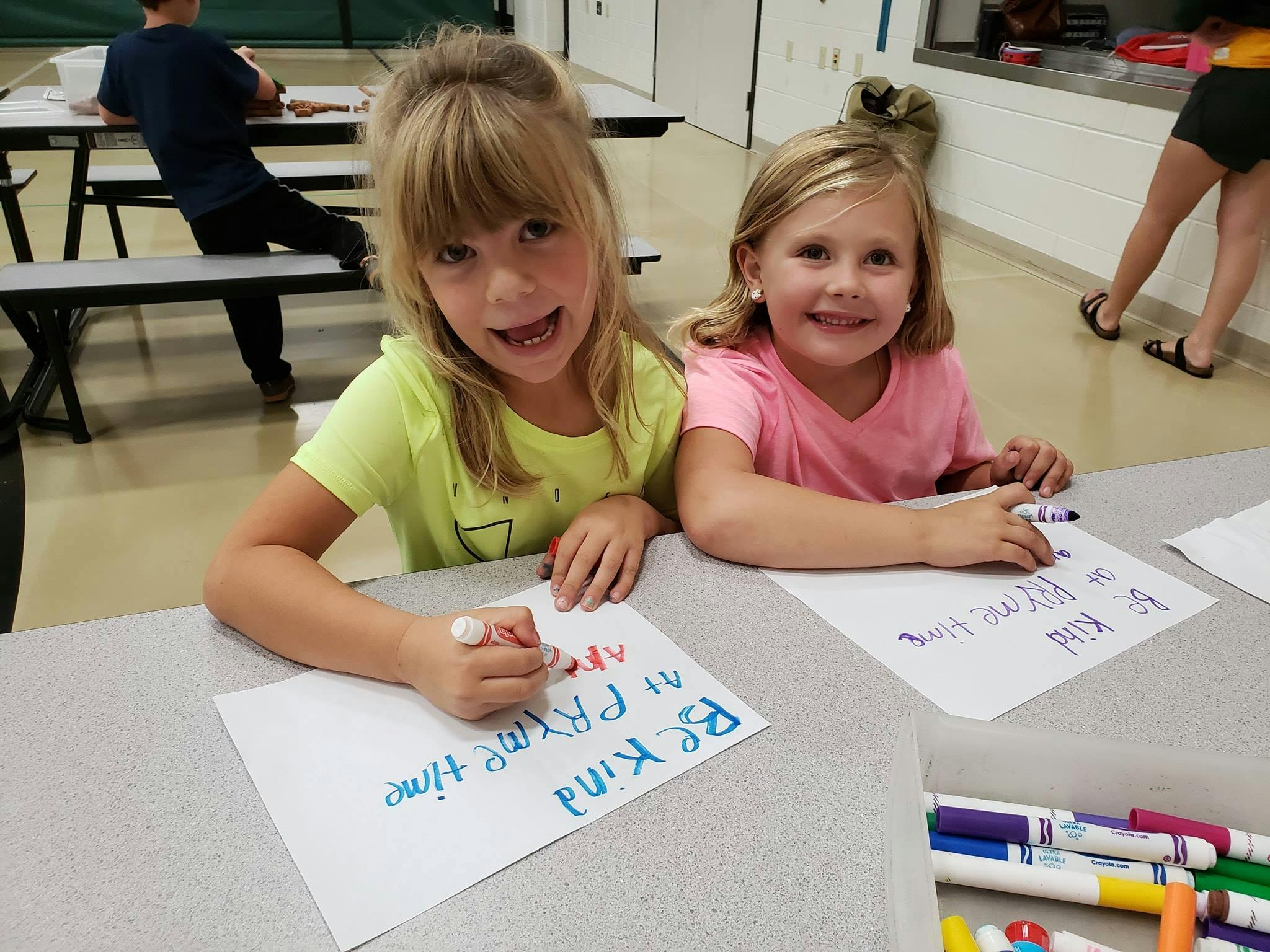 Two children drawing on paper with markers